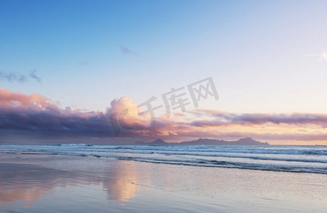 美丽的日落在海洋海滩，新西兰。令人愉快的自然和旅行背景