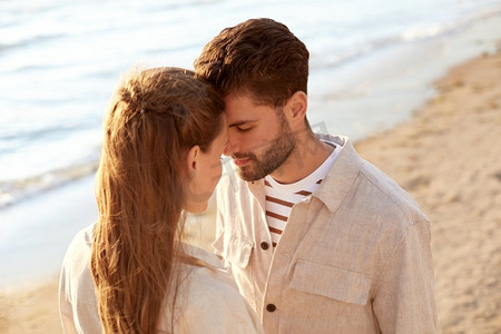 眼睛度假摄影照片_休闲，关系和人的概念—快乐的夫妇闭上眼睛在夏季海滩。快乐的夫妇与关闭的眼睛在夏季海滩