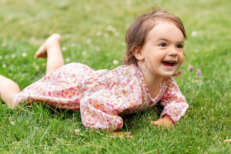 童年、休闲和人的概念--夏日躺在草地上微笑的小女婴。快乐的小女婴在夏天躺在草地上