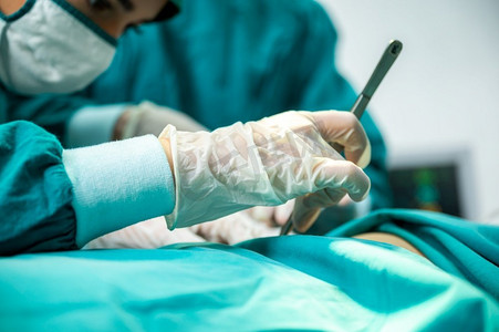 医生护理摄影照片_外科医生的医疗团队在医院做手术干预，手术操作使用医疗设备的过程. 