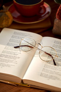 阅读、季节与休闲理念--秋季家中打开的诗集与眼镜特写。翻开的诗集和眼镜特写
