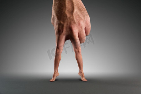 行走男摄影照片_男性的手，腿而不是手指压在灰色上。有腿的男手