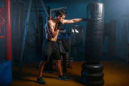 足球训练营摄影照片_肌肉发达的男子在健身房训练时选择沉重的哑铃。在体育俱乐部健身，健康的生活方式，健康的锻炼
