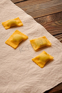 清绿色摄影照片_美味的生的自制馄饨意大利面与菠菜和意大利乳清干酪在木的乡村背景。制作意大利馄饨的过程。 
