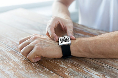 技术，健康和人的概念—关闭男性手与二维码在智能手表。男性手与二维码智能手表