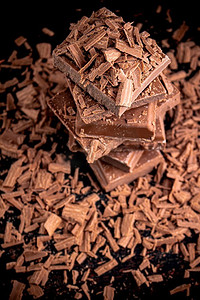 点心背景摄影照片_碎块和磨碎的黑巧克力。在黑色的背景上..碎块和磨碎的黑巧克力。