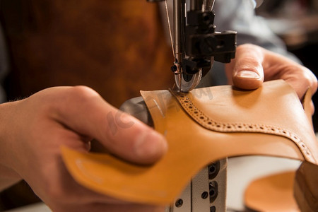 一个修鞋匠缝合鞋的一部分的特写在车间。一个鞋匠缝合鞋的一部分特写