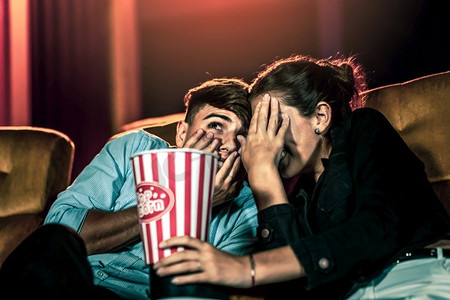 情侣白色摄影照片_一对情侣看电影震惊和眼睛关闭在电影院电影院。