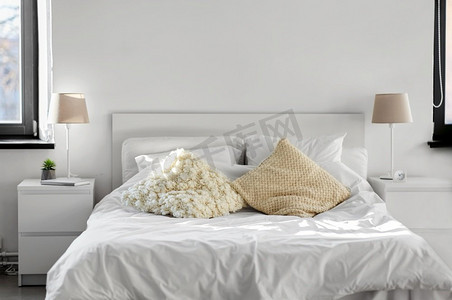 舒适，室内和生活的概念—舒适的卧室与垫子和床上用品在家里。舒适的卧室有靠垫和床单在家里