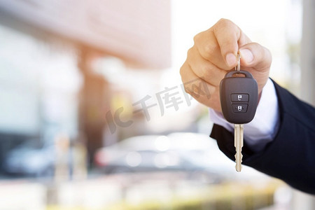 汽车销售员正在陈列室把新车钥匙交给顾客。