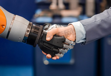 cyborg摄影照片_一个商人与Android机器人握手的手。人类与人工智能交互的概念。