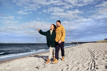 爱情、关系和人的概念-幸福的情侣走在秋天的海滩上。一对情侣沿着秋天的海滩散步