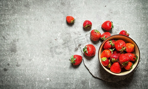盛在碗里的成熟草莓。在石桌上..盛在碗里的成熟草莓。