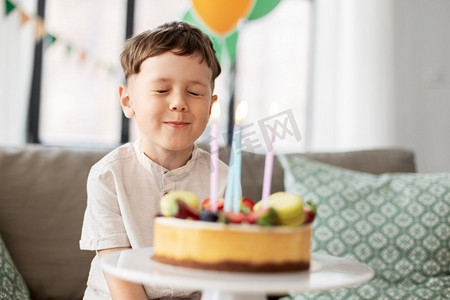节日，庆祝和人的概念—快乐的小男孩与生日蛋糕做的愿望在家庭聚会。小男孩与生日蛋糕做愿望