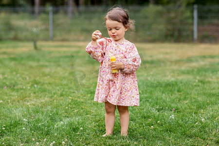 童年、休闲和人的概念快乐的小女婴在夏天吹肥皂泡。快乐的女婴在夏天吹肥皂泡