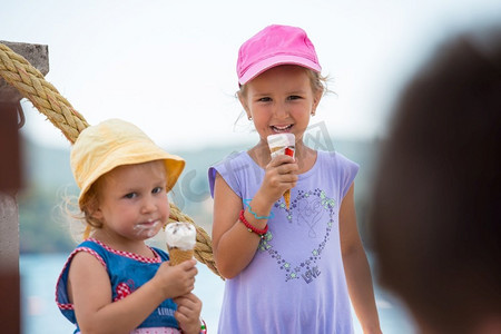 可爱的小女孩吃冰淇淋在海边在暑假期间