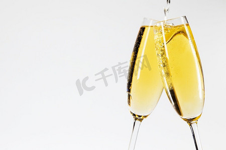 玻璃杯子摄影照片_香槟倒在两杯新年庆祝。香槟倒在两个杯子里