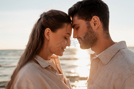 眼睛度假摄影照片_休闲，关系和人的概念—快乐的夫妇闭上眼睛在夏季海滩。快乐的夫妇与关闭的眼睛在夏季海滩