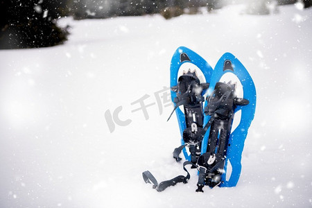 冬天在山上徒步旅行在下雪的冬日，蓝色的雪鞋新鲜地展示着周围的雪花