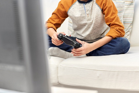 休闲、科技和人的概念--戴着游戏手柄在家玩电子游戏的男孩。戴着游戏手柄在家玩电子游戏的男孩