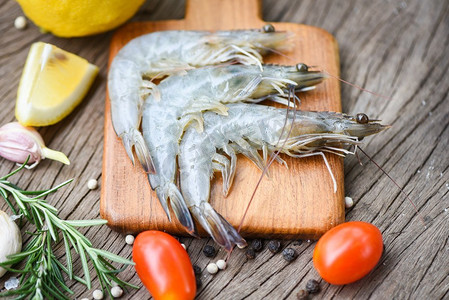 鲜虾在木砧板上，配有香草和香料用于烹饪海鲜/生虾虾