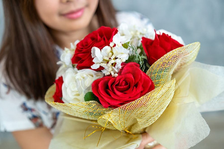 快乐的女人得到玫瑰花束礼物从她的男朋友在情人节。夫妻爱的生活方式概念。