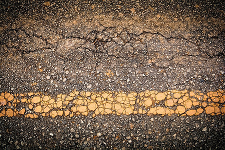 黄黑色摄影照片_裂缝沥青旧道路纹理背景与黄线