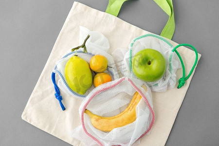 食物购物，再用及生态概念—可再用的袋子，以灰色背景与水果。可重复使用的水果食品购物袋