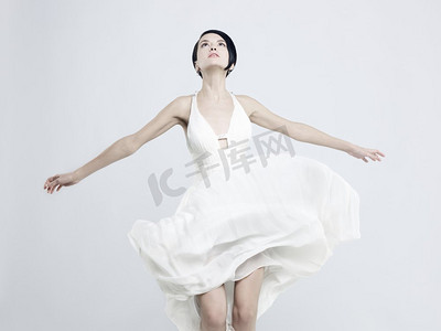 穿着飘逸的白色连衣裙的美丽年轻女士的时尚照片
