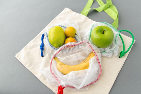 食物购物，再用及生态概念—可再用的袋子，以灰色背景与水果。可重复使用的水果食品购物袋