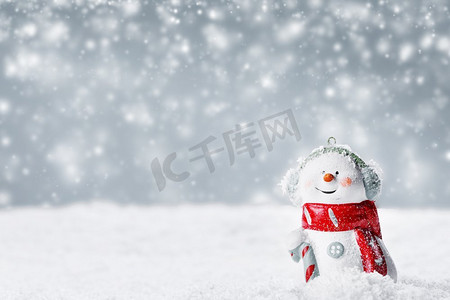 进烟囱的圣诞老人摄影照片_圣诞雪人玩具，背景是冬天的雪地。冬日背景下的雪人玩具