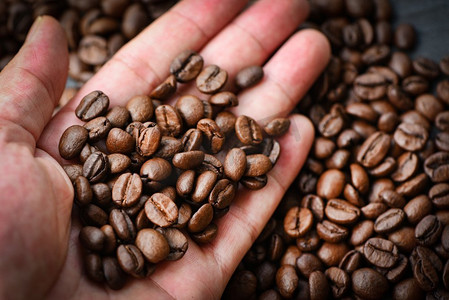 咖啡豆在手和咖啡豆烘焙背景 