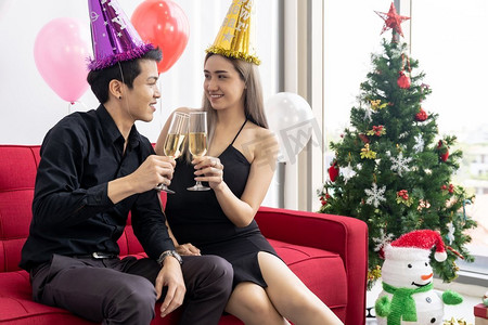 大城市摄影照片_一对年轻的亚洲成年夫妇在大城市大公寓的客厅里一起喝着汽酒庆祝新年圣诞假期