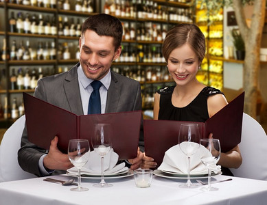酒吧菜单摄影照片_休闲和豪华概念—有菜单的微笑夫妇在餐馆或葡萄酒酒吧背景。微笑的夫妇与菜单在餐厅