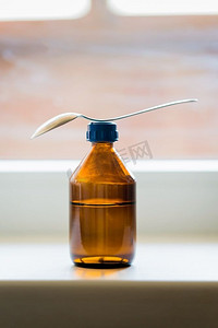 止咳摄影照片_靠窗的带勺子的止咳糖浆瓶