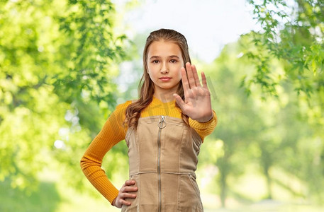 生态停车摄影照片_生态、禁忌与人的理念--青春期少女在绿色自然背景下做停车手势。十几岁的女孩做着停车的手势