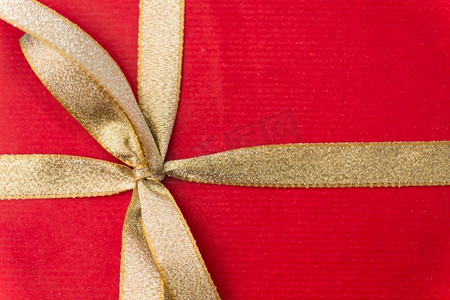 节日，问候和惊喜概念-金色蝴蝶结圣诞红色礼盒特写。圣诞红色金色蝴蝶结礼盒特写