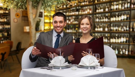 休闲和豪华概念—有菜单的微笑夫妇在餐馆或葡萄酒酒吧背景。微笑的夫妇与菜单在餐厅