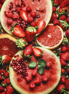 红色水果和浆果背景，带有西瓜、葡萄柚、草莓、覆盆子和石榴籽。健康的夏季食物。俯视图。