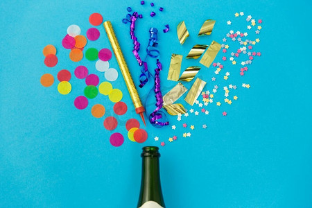 庆祝和装饰概念香槟瓶和生日聚会道具在蓝色背景。香槟瓶与生日派对道具在蓝色
