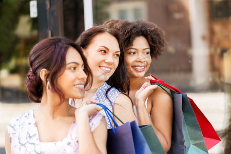 销售，消费主义和人的概念—快乐的年轻妇女与购物袋在城市街道。快乐的妇女与购物袋在城市