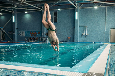 游泳者在护目镜从塔跳入水，训练在游泳池，健康的活动。水下运动