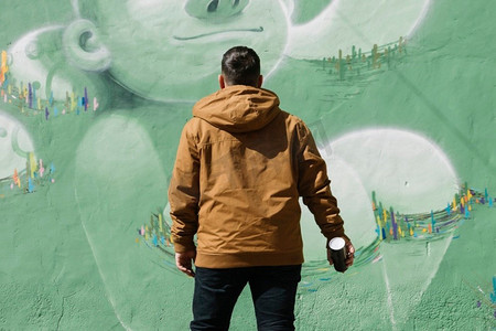 艺术家站在涂鸦墙上，拿着气雾剂可以手