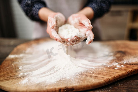 女的手在砧板上把面团夹在面粉里。蛋糕烹饪