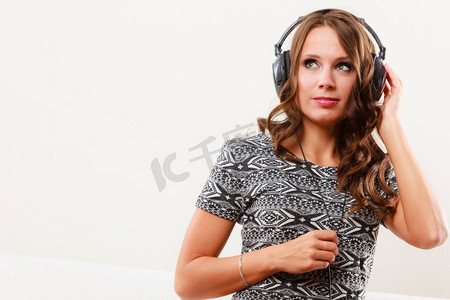 人们休闲放松的观念。年轻女子在大耳机听音乐mp3放松在家