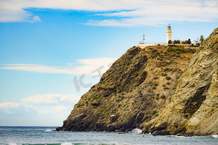 灯塔海边摄影照片_海岸景观与Carchuna灯塔。热带海岸，格拉纳达。西班牙安达卢西亚。旅游景点西班牙海岸与Carchuna灯塔