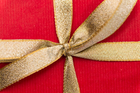 节日，问候和惊喜概念—关闭圣诞节红色礼品盒与金色蝴蝶结。关闭圣诞节红色礼品盒与金色蝴蝶结