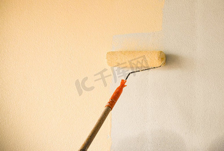 油漆摄影照片_手画墙背景与油漆滚筒在建筑工地内部装饰 