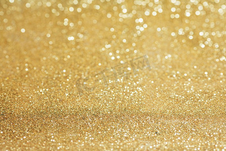 金色灯光背景摄影照片_闪亮的金bokeh闪光的光抽象背景，圣诞节新年聚会庆祝概念。闪亮的金色灯光背景