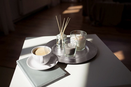 卫生和芳香疗法的概念-咖啡，蜡烛，书籍和香草扩散器在家里的桌子上。桌子上有咖啡、蜡烛和香料扩散器